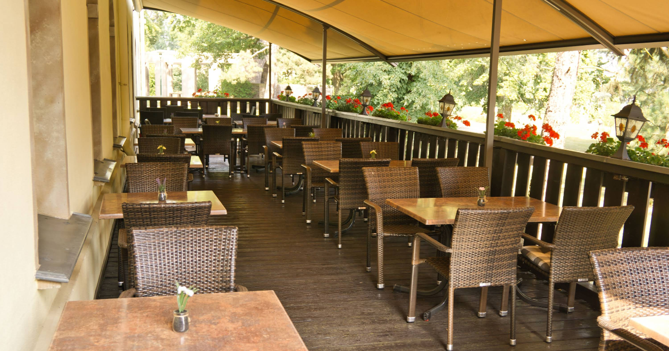 Gemütlicher Biergarten mit Lichterketten und Olivenbäumen